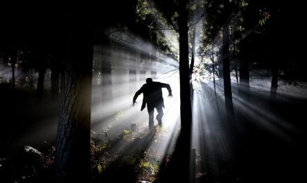 Frankenstein-type monster running in the dark forest with light behind him